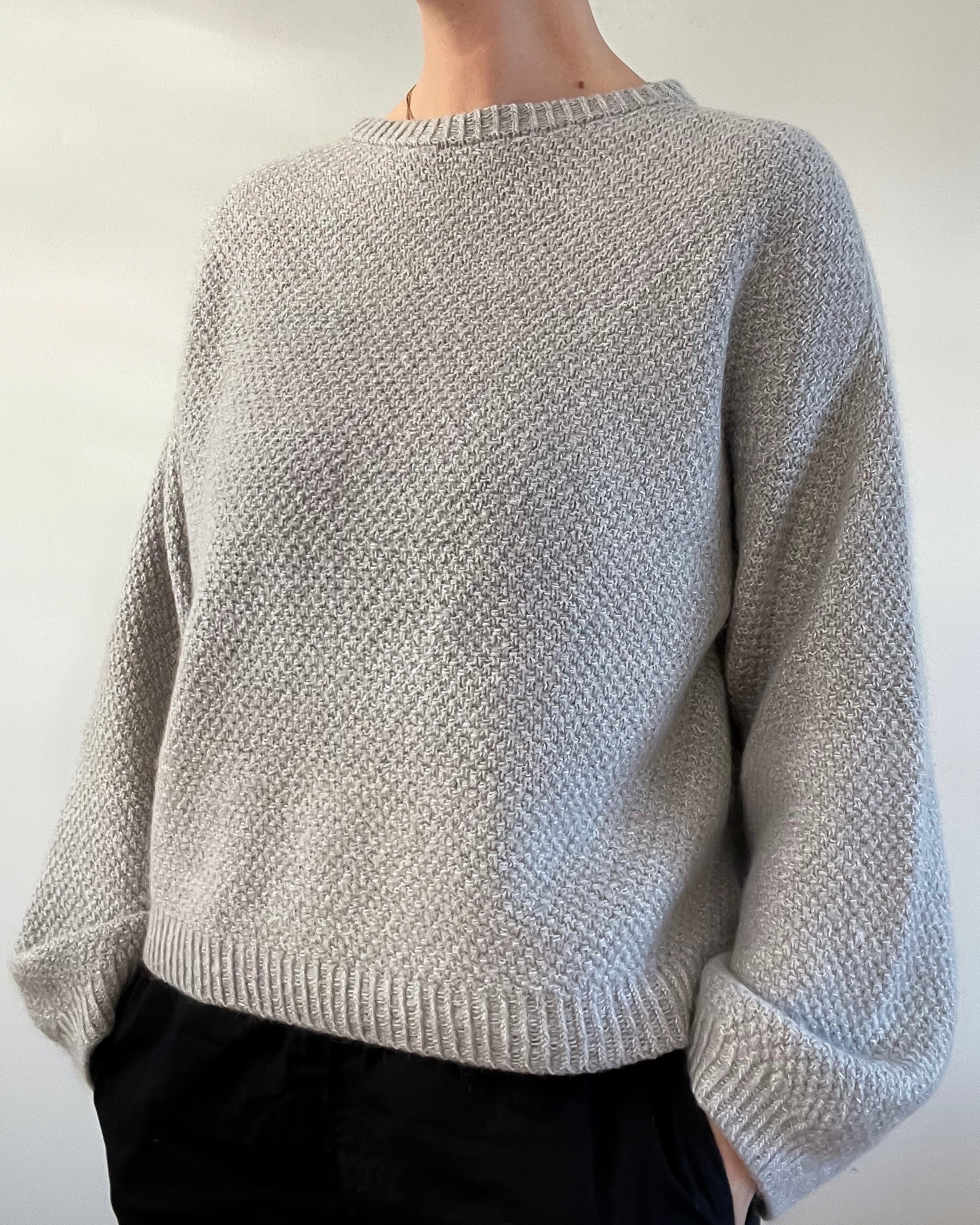 Photo of a woman wearing a beige version of the Bondi Sweater - a hand knit sweater by Berthyknit worked in double moss stitch. 